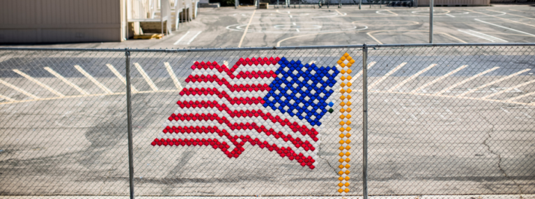 American flag on chain link fence outside of a school yard