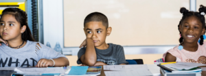 Three students sitting at desk and listening to lesson