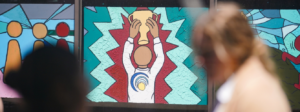 Mural of a faceless child holding up a trophy with blurred children moving in the foreground.