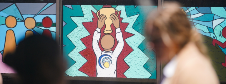 Mural of a faceless child holding up a trophy with blurred children moving in the foreground.